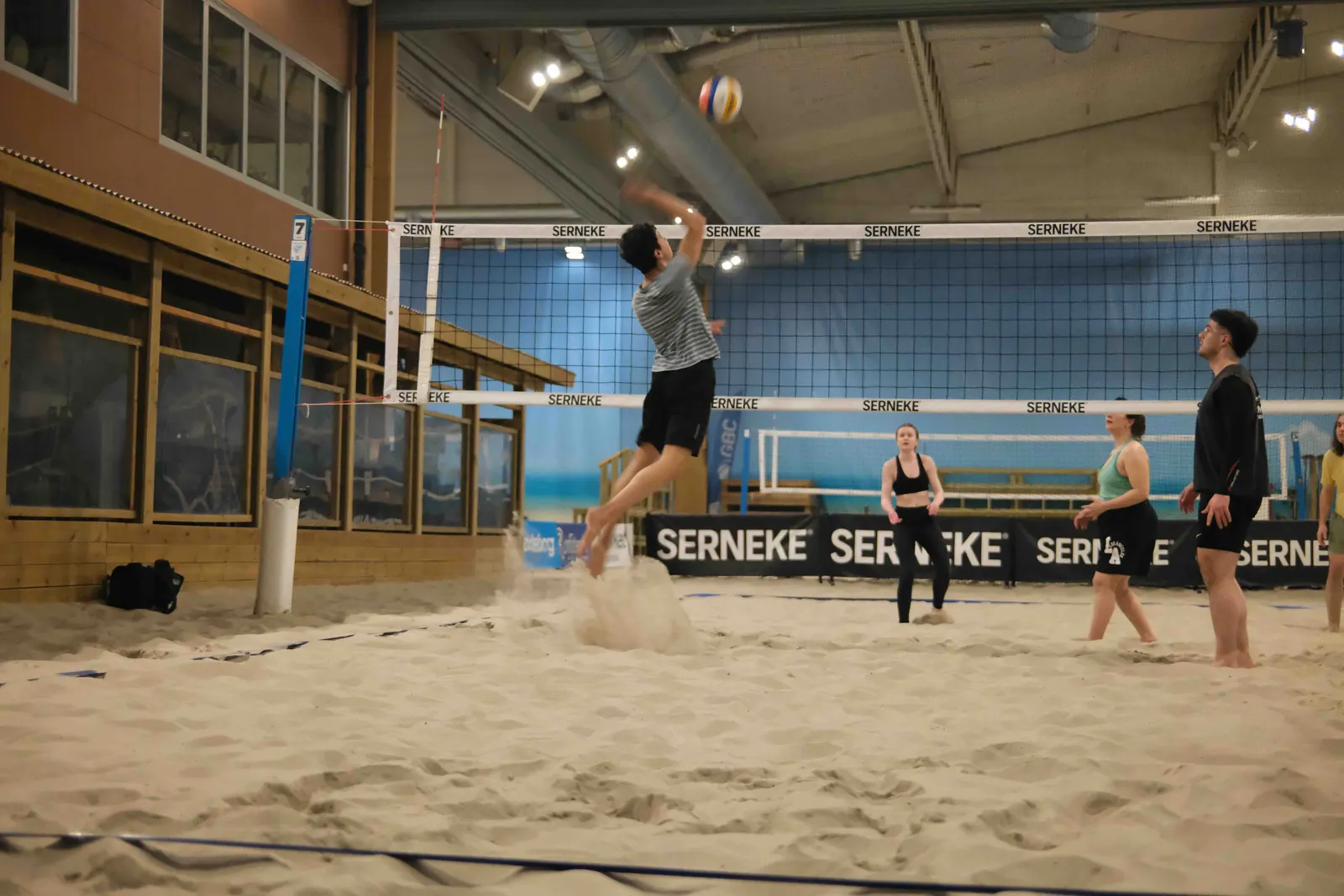 Students playing beach volleyball indoors.