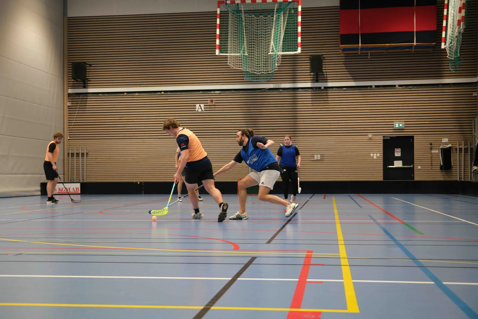 Students playing floorball in a sports hall.