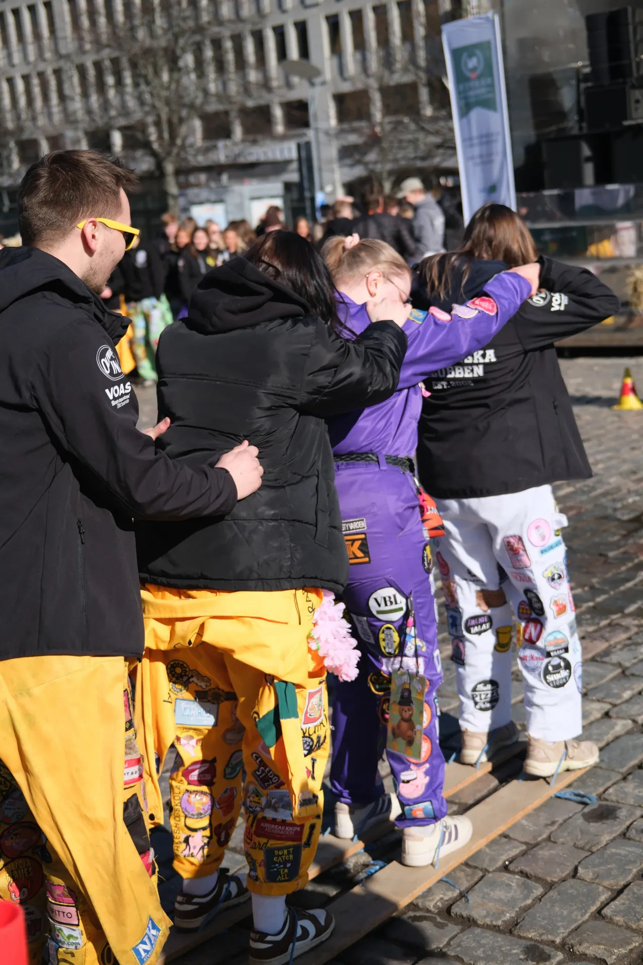 Studenter som står utomhus med armarna om varandra.
