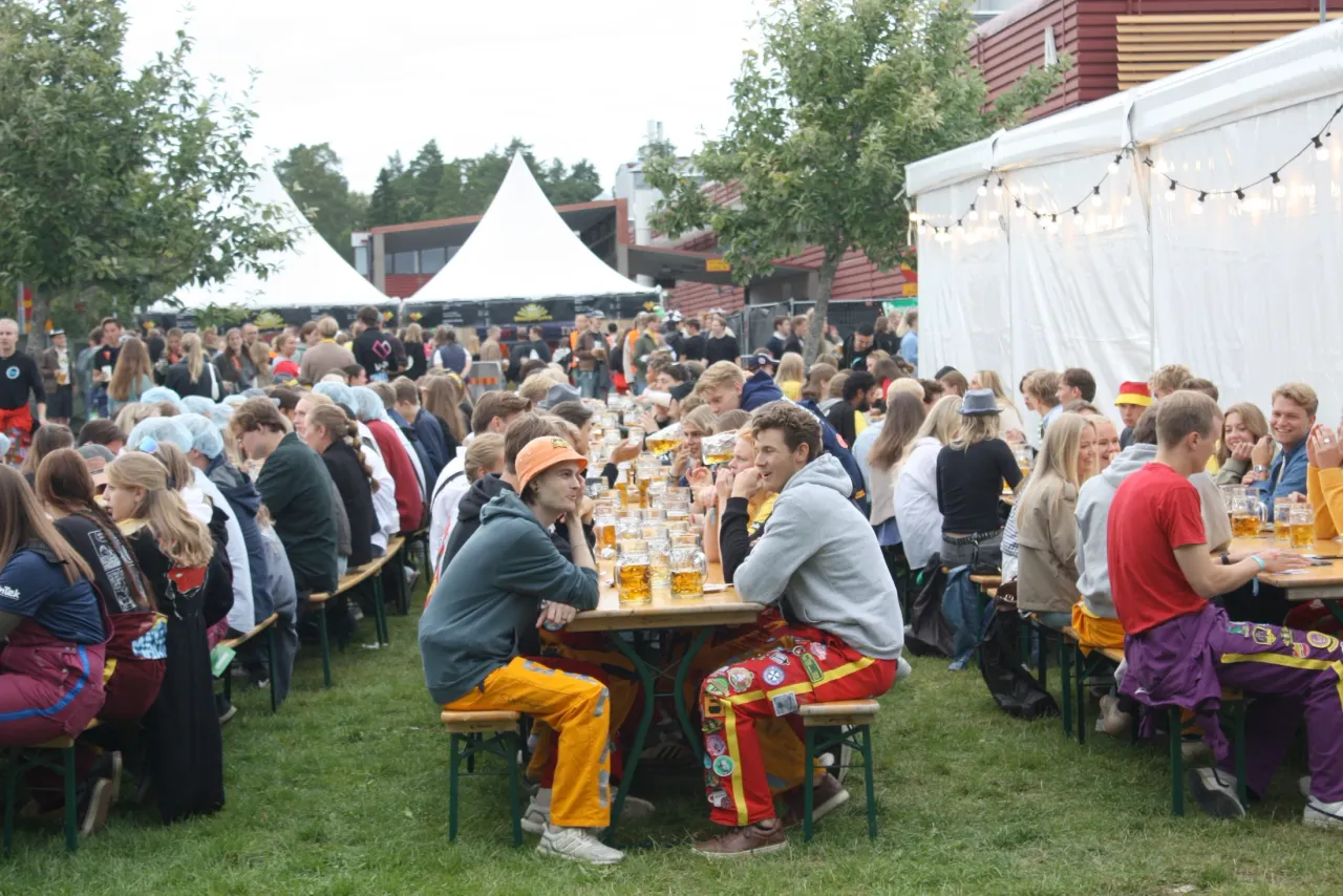 Studenter som delar en måltid vid långa utomhusborden under en sammankomst på campus.